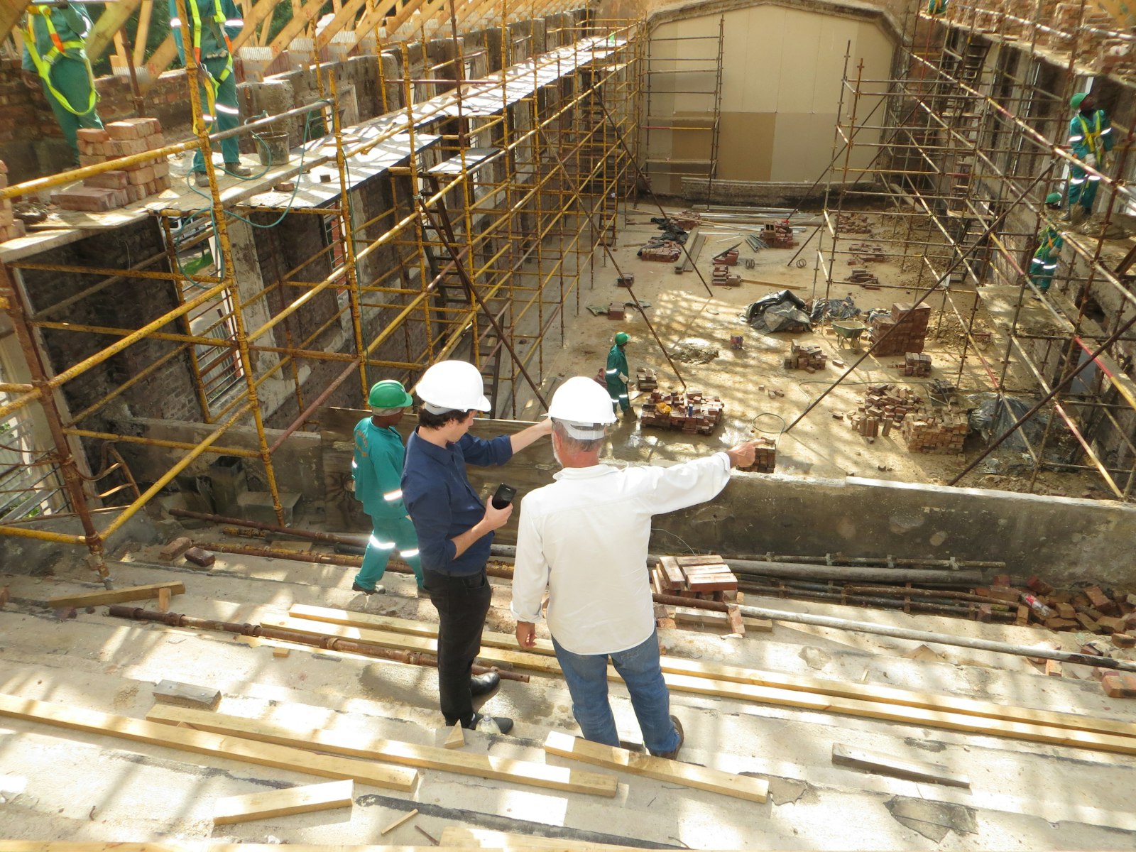 5 điều cần chuẩn bị trước khi xây nhà dành cho gia chủ 11 Hai người đội mũ bảo hộ chỉ vào công trình đang thi công - lập kế hoạch xây nhà